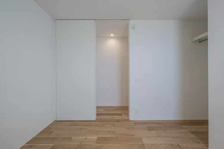 木目床と落ち着いた白色の壁紙で構成された洋室。